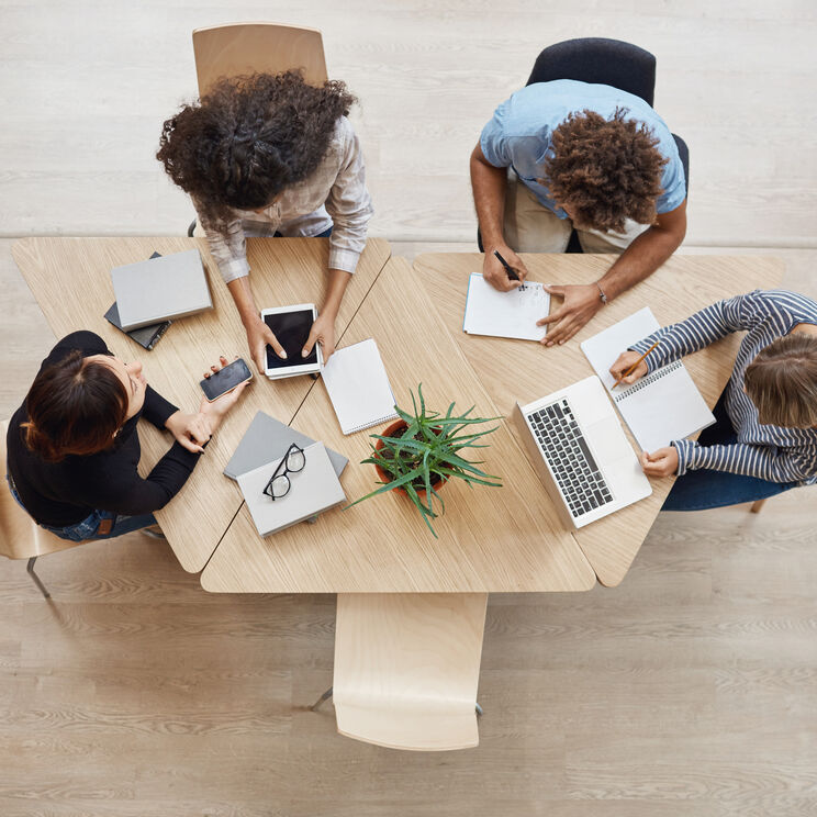 View from business startup teamwork concept startup partners sitting coworking space talking about future project looking through examples work laptop digital tablet